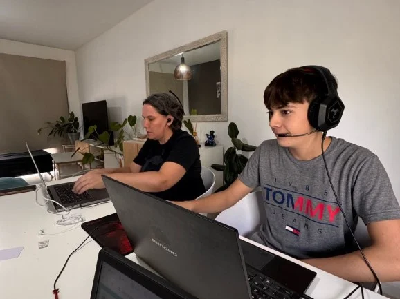 Photo of two participants of the mini-hackathon participating on their computers from the same location.